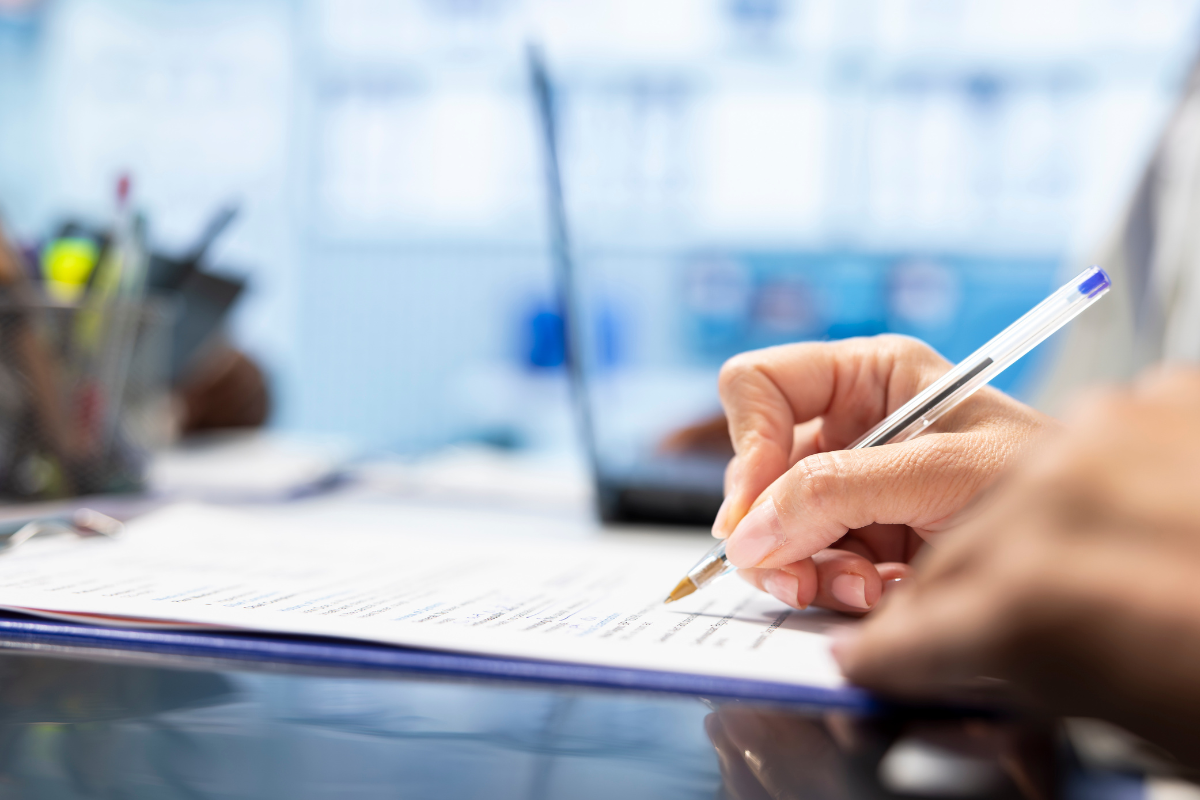 Empregos Paraíba Pessoa assinando documento com caneta azul em escritório moderno