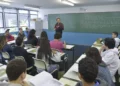 Professor ensina alunos em sala de aula com lousa e carteiras organizadas, educação escolar em 2026