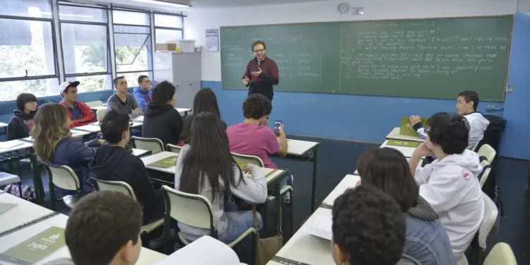 Professor ensina alunos em sala de aula com lousa e carteiras organizadas, educação escolar em 2026
