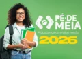 Jovem segurando cadernos com sorriso, em fundo verde, representando o programa Pé-de-Meia 2026, com informações sobre consulta online e o calendário do ensino médio.