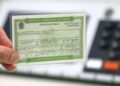 Mão segurando um título eleitoral brasileiro com detalhes de identificação biométrica e informações pessoais.
