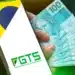 Imagem mostrando a tela de um celular com o logo do FGTS, junto a uma mão segurando várias cédulas de 100 reais, ilustrando o Saque-aniversário 2026.