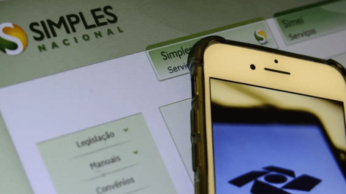 Celular diante da página do Simples Nacional representa a escolha entre regime puro e híbrido para recolhimento de tributos.