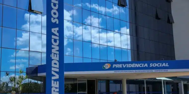 Fachada do prédio do INSS com o nome 'Previdência Social' visível e um céu refletido nas janelas.
