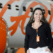 Mulher com crachá da Gol sorrindo em frente a avião com logo da Gol em destaque