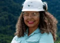 Funcionária da Vale sorrindo, com equipamentos de segurança, em ambiente de trabalho externo. Oportunidades de emprego na Vale.