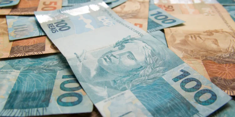 Cédulas de dinheiro real, incluindo notas de 50 e 100 reais, ilustrando o pagamento do 13º salário para beneficiários do INSS.