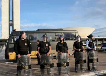 Policiais legislativos federais em frente à Câmara dos Deputados, com escudos e uniforme, preparados para a segurança.