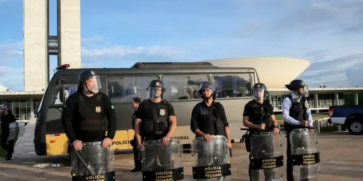 Policiais legislativos federais em frente à Câmara dos Deputados, com escudos e uniforme, preparados para a segurança.