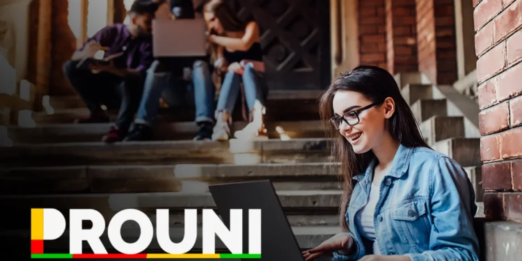 Estudante feliz utilizando laptop com o logo do Programa Universidade Para Todos (Prouni) ao fundo, representando a divulgação do resultado da primeira chamada para 2026.