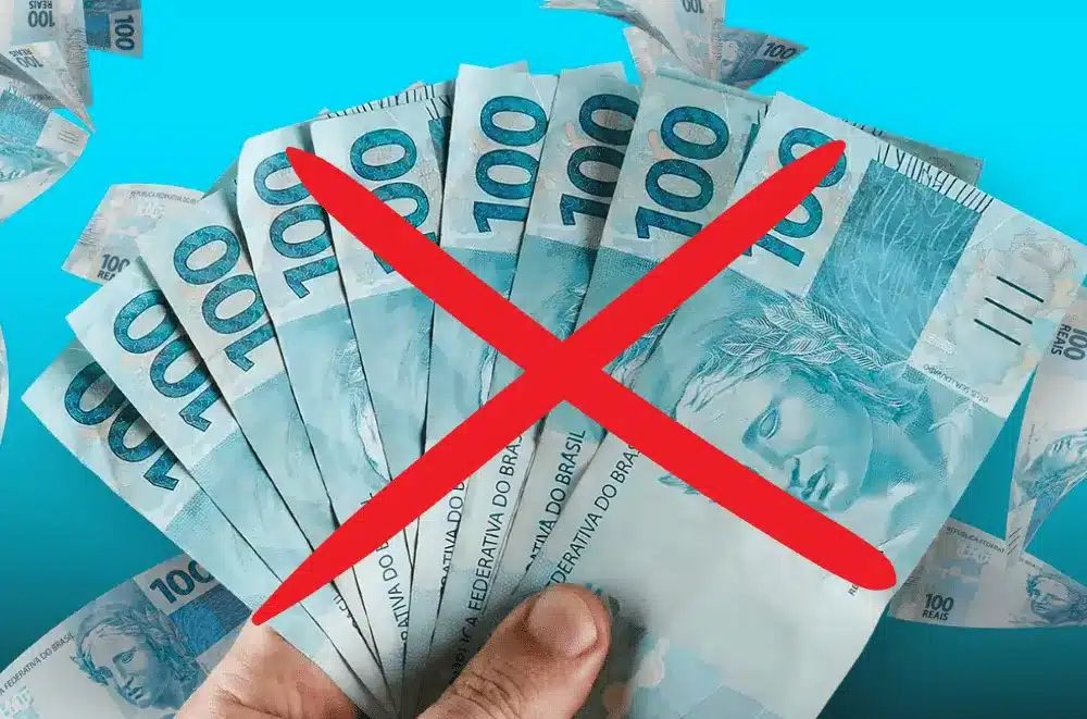 Beneficiários do BPC sem 13º salário em 2026 Notas de 100 reais seguradas por uma mão com símbolo de proibição representando falta do 13º salário para beneficiários do BPC em 2026