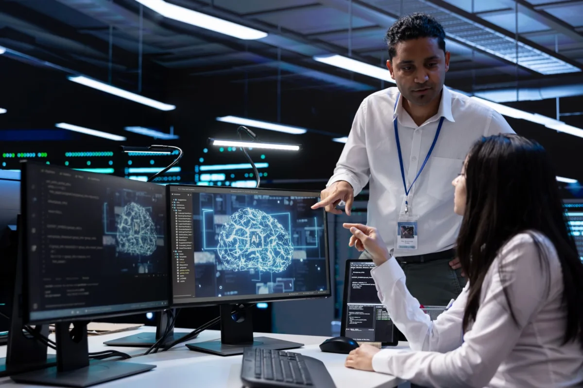 Carreiras ligadas à inteligência artificial Engenheiros de IA discutindo projetos em um ambiente de alta tecnologia, com gráficos de inteligência artificial na tela.