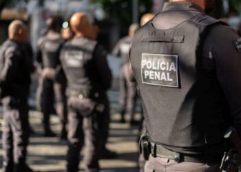 Grupo de policiais penitenciários em treinamento, com uniformes e coletes, durante ação de segurança.