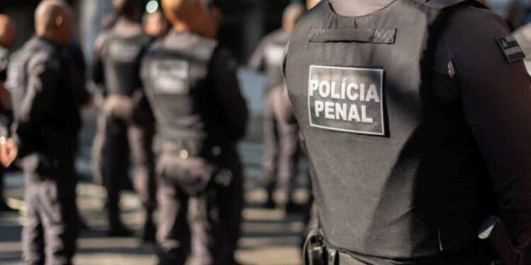 Grupo de policiais penitenciários em treinamento, com uniformes e coletes, durante ação de segurança.