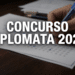 Mão preenchendo prova de concurso com caneta azul, sobre uma folha de teste, com texto 'Concurso Diplomata 2026' em destaque.