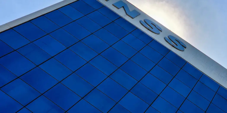 Prédio envidraçado do INSS refletindo o céu com letreiro visível no topo