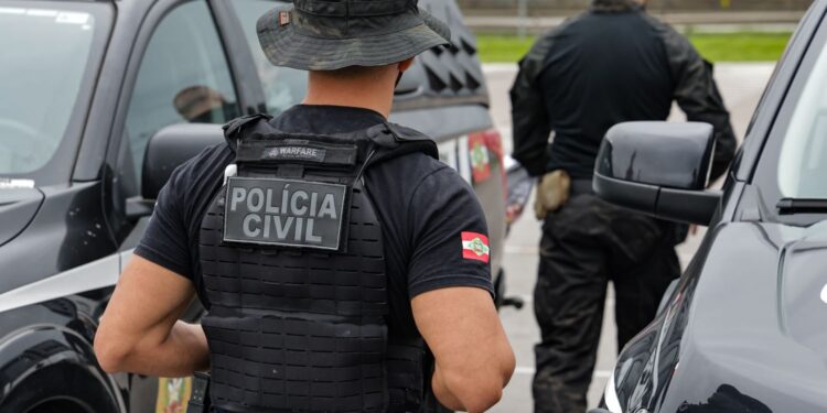 Policiais civis fardados próximos a viaturas durante ação no exterior