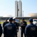 Grupo de policiais legislativos federais conversa em frente ao Congresso Nacional, viaturas ao fundo