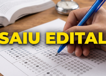 Pessoa preenche cartão resposta de concurso com caneta azul ao lado de livro