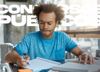 Homem jovem com cabelo afro e camiseta azul, focado e escrevendo em um caderno enquanto estuda. Ao fundo, o texto sobreposto diz "CONCURSOS PÚBLICOS".