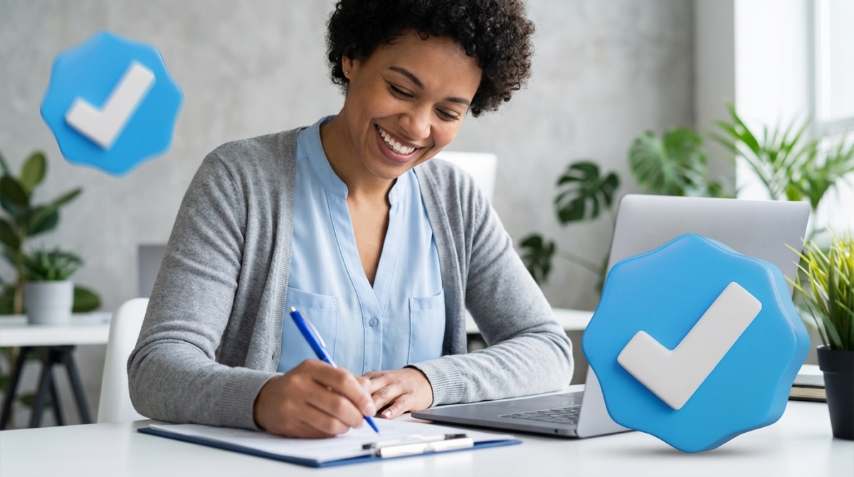 Concursos Prefeituras SP 2026 Mulher sorridente escreve em prancheta ao lado de notebook com ícones de verificação azul ao fundo