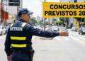 Agente do Detran faz sinalização em rua movimentada com faixa de concursos previstos 2026