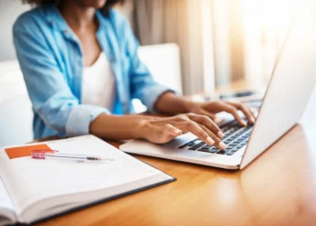 Mulher utilizando notebook para acessar informações sobre editais de prefeituras com inscrições nos últimos dias.