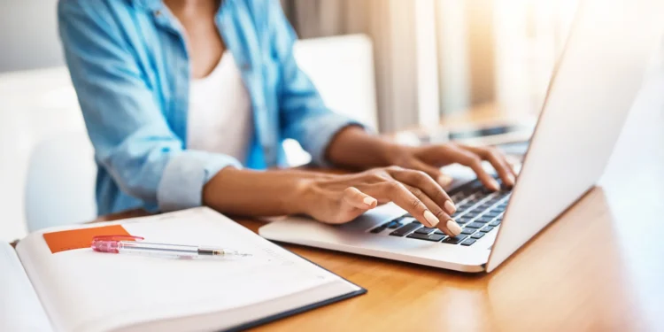 Mulher utilizando notebook para acessar informações sobre editais de prefeituras com inscrições nos últimos dias.