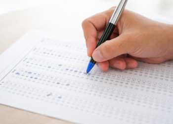 Pessoa marca respostas com caneta azul em folha de gabarito de múltipla escolha