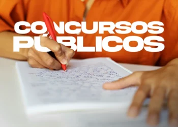 Pessoa escrevendo em caderno com caneta vermelha e texto concursos públicos representando preparação para provas