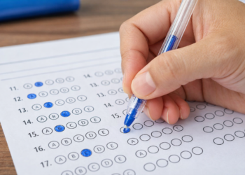 Pessoa marcando alternativas em cartão-resposta com caneta azul