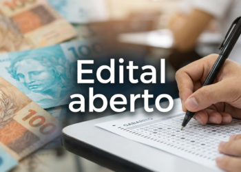 Mão preenchendo cartão-resposta ao lado de notas de cem reais e texto edital aberto