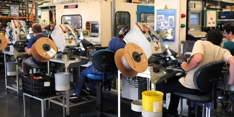 Trabalhadores em uma linha de produção com equipamentos e ferramentas industriais