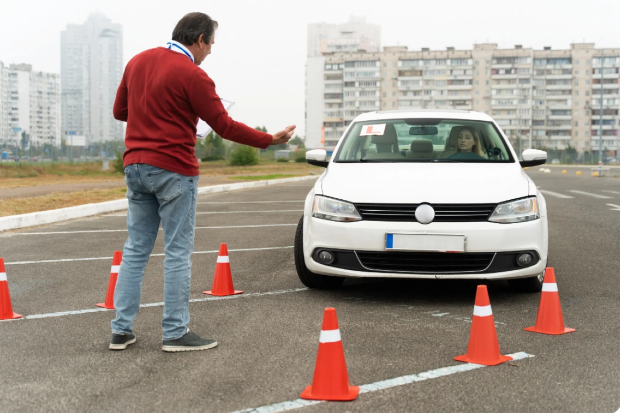 Fim da baliza como fase eliminatória na prova de CNH Instrutor orientando aluno durante manobra de estacionamento, com cones, em prova de direção.