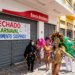 Grupo fantasiado e banda de metais desfilam em frente a agência bancária fechada durante o Carnaval