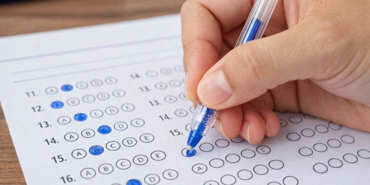 Pessoa marca alternativas com caneta azul em folha de gabarito de múltipla escolha