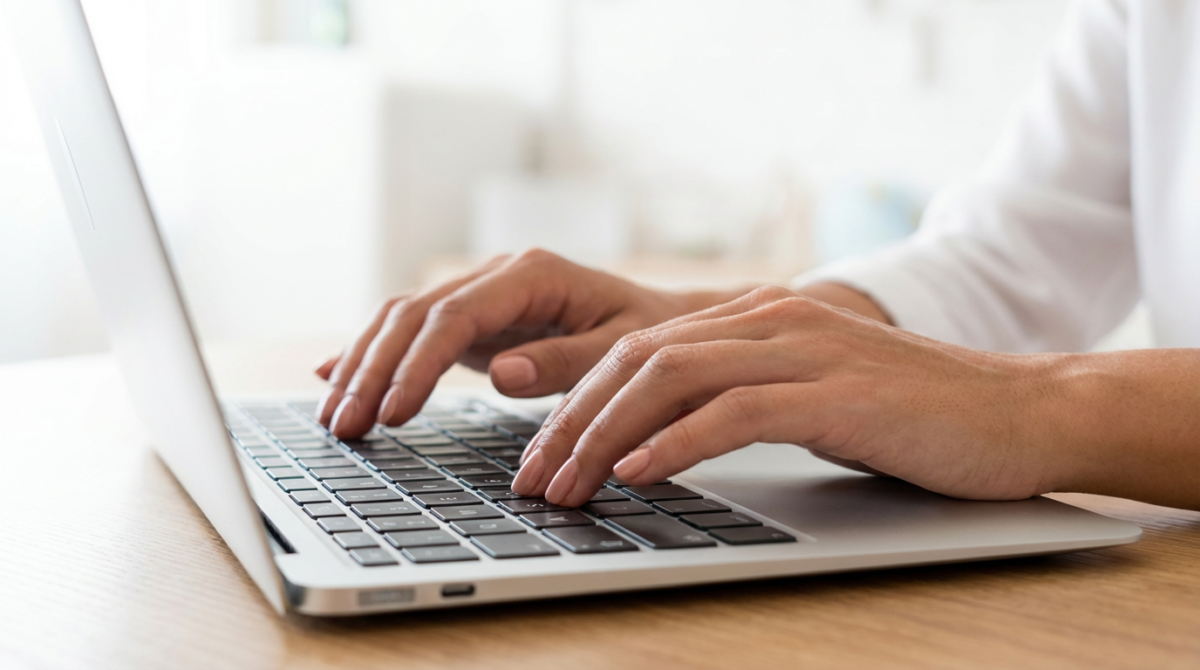 Inscrição Concurso IFCE 2026 Mãos sobre teclado de notebook, pessoa digitando formulário online em ambiente iluminado