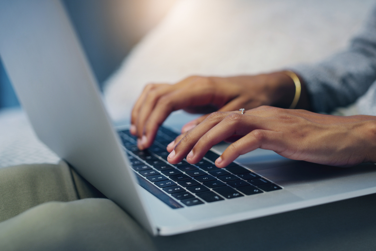 Inscrição Prefeitura Mãos femininas digitando em teclado de notebook prateado sobre colo