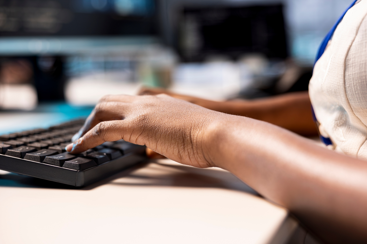 Inscrição Prefeitura Mãos de pessoa digitando em teclado preto com tela de computador ao fundo