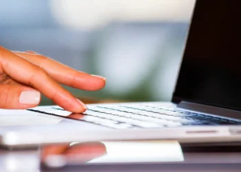 Pessoa digitando em um laptop, representando a inscrição e o processo digital para o programa Bolsa Atleta.