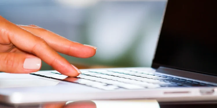 Pessoa digitando em um laptop, representando a inscrição e o processo digital para o programa Bolsa Atleta.