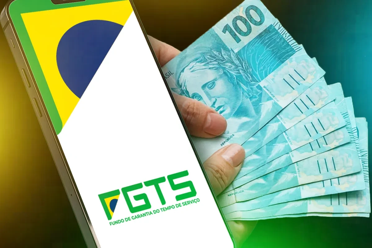Liberação extraordinária do FGTS para saque-aniversário Mãos segurando notas de cem reais ao lado do aplicativo do FGTS aberto no celular