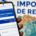Pessoa acessando site da Receita Federal no celular, com cédulas de dinheiro ao fundo.
