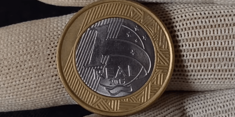 Close-up macro da moeda de 1 real das Olimpíadas Rio 2016, modalidade canoagem, com destaque para a região do pescoço do atleta, onde se localiza o erro de cunhagem da data marcada invertida.