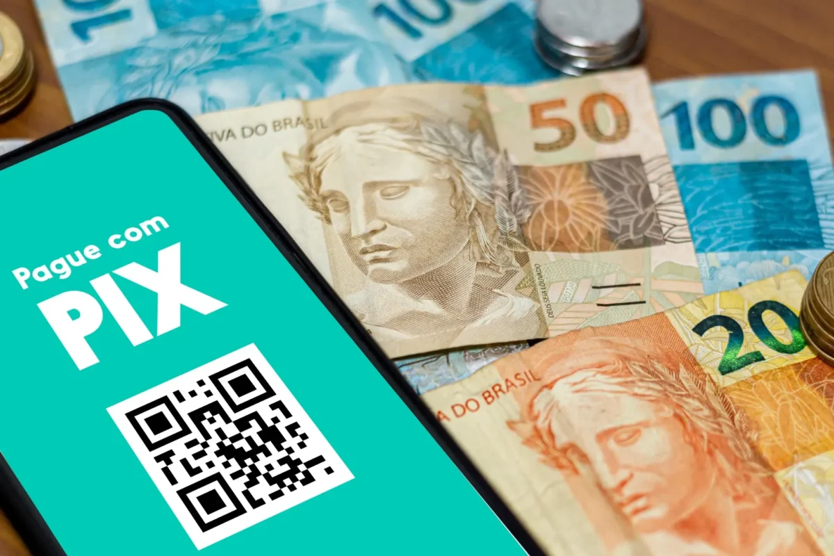 Novas regras aumentam chances de vítimas reaverem valores perdidos. Celular exibindo pagamento via Pix com QR Code ao lado de cédulas de real, ilustrando rastreamento e devolução de valores após golpes.