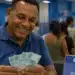 Homem segura notas de real em agência bancária, representando o pagamento de até R$ 1.621 do abono PIS/Pasep 2026.