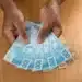 Pessoa segurando notas de cem e cinquenta reais simbolizando o pagamento do Pé-de-Meia.