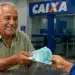 Idoso brasileiro recebendo cédulas de real em agência bancária, representando os pagamentos do INSS nesta semana, entre os dias 27 e 31 de julho.