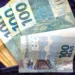 Notas de R$ 100,00, representando a liberação de R$ 1.200 do programa Pé-de-Meia pelo governo.
