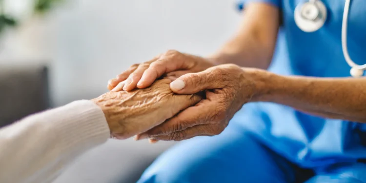 Médico segurando as mãos de um paciente idoso em um gesto de apoio e cuidado, ilustrando a importância de profissões estáveis como a medicina no Brasil.